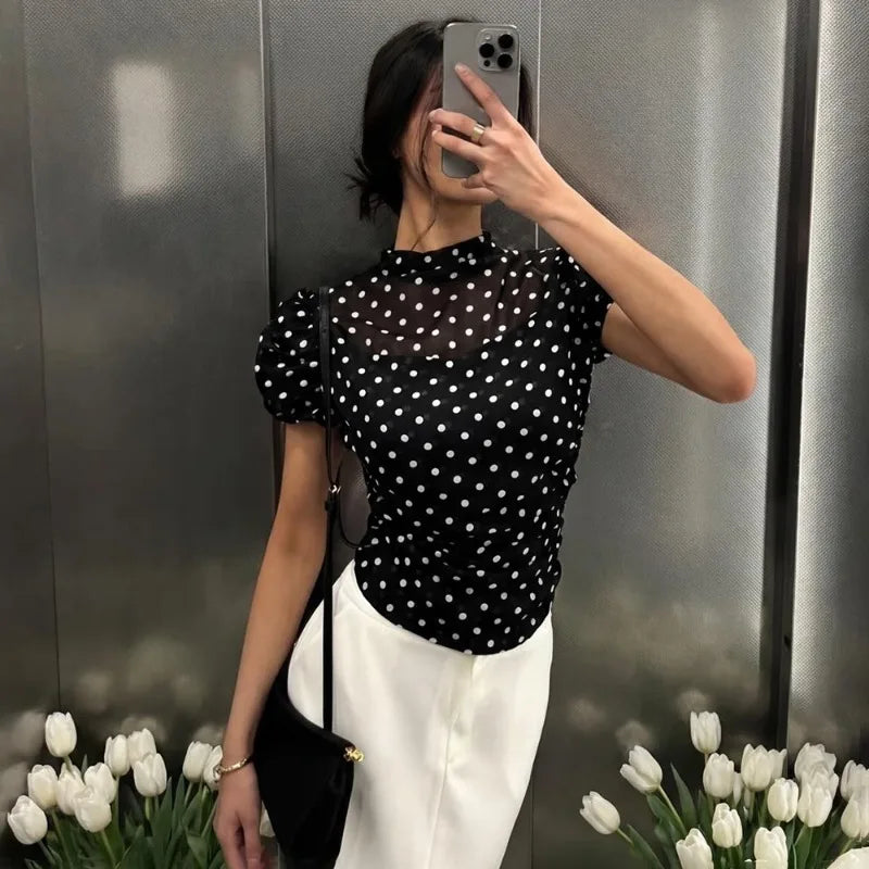 Woman wearing black polka dot mesh top and white pants