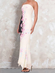 Woman wearing a strapless dress with floral patterns against a textured wall.