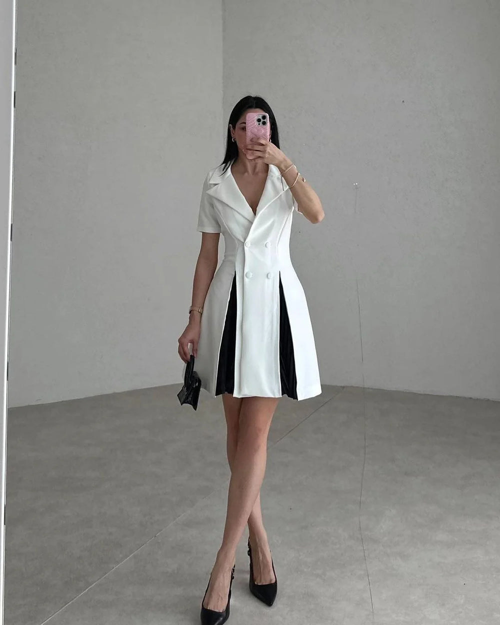 Woman wearing a white dress with black accents in a minimalistic setting