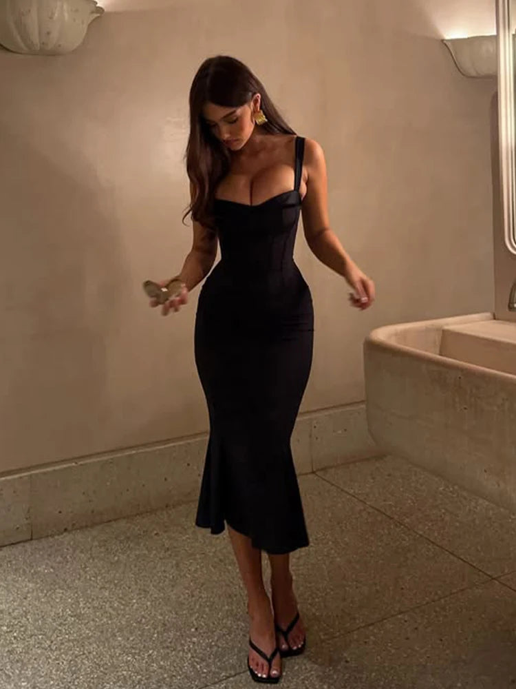 Woman in a black dress standing in a bathroom.