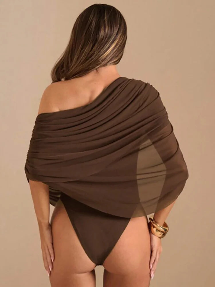 Woman wearing a brown off-shoulder garment against a beige background