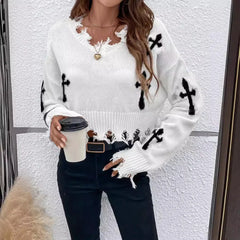 Woman wearing a white sweater with black patterns, holding a coffee cup against a white wall.