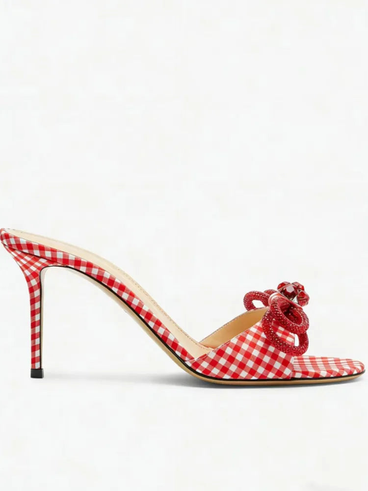 Red and white checkered high-heeled shoe with a bow on a white background