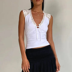 Woman wearing a white sleeveless top with lace details and a black skirt on a plain background