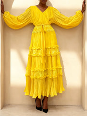 Yellow dress with ruffled layers worn by a person against a neutral background