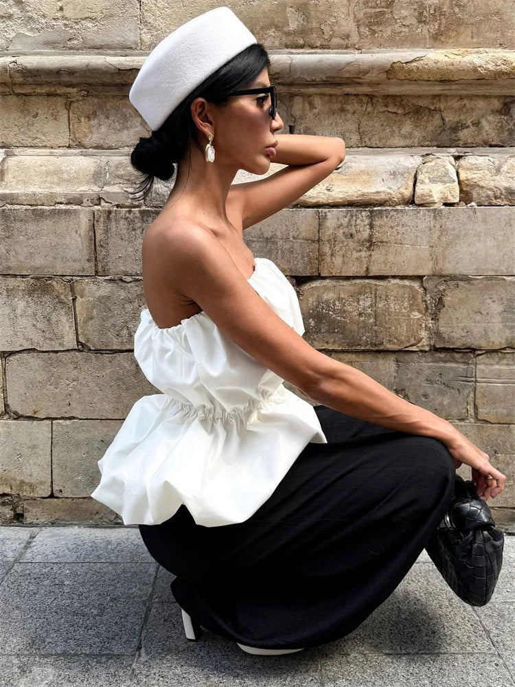 Woman in a white top and black pants sitting on stone steps.