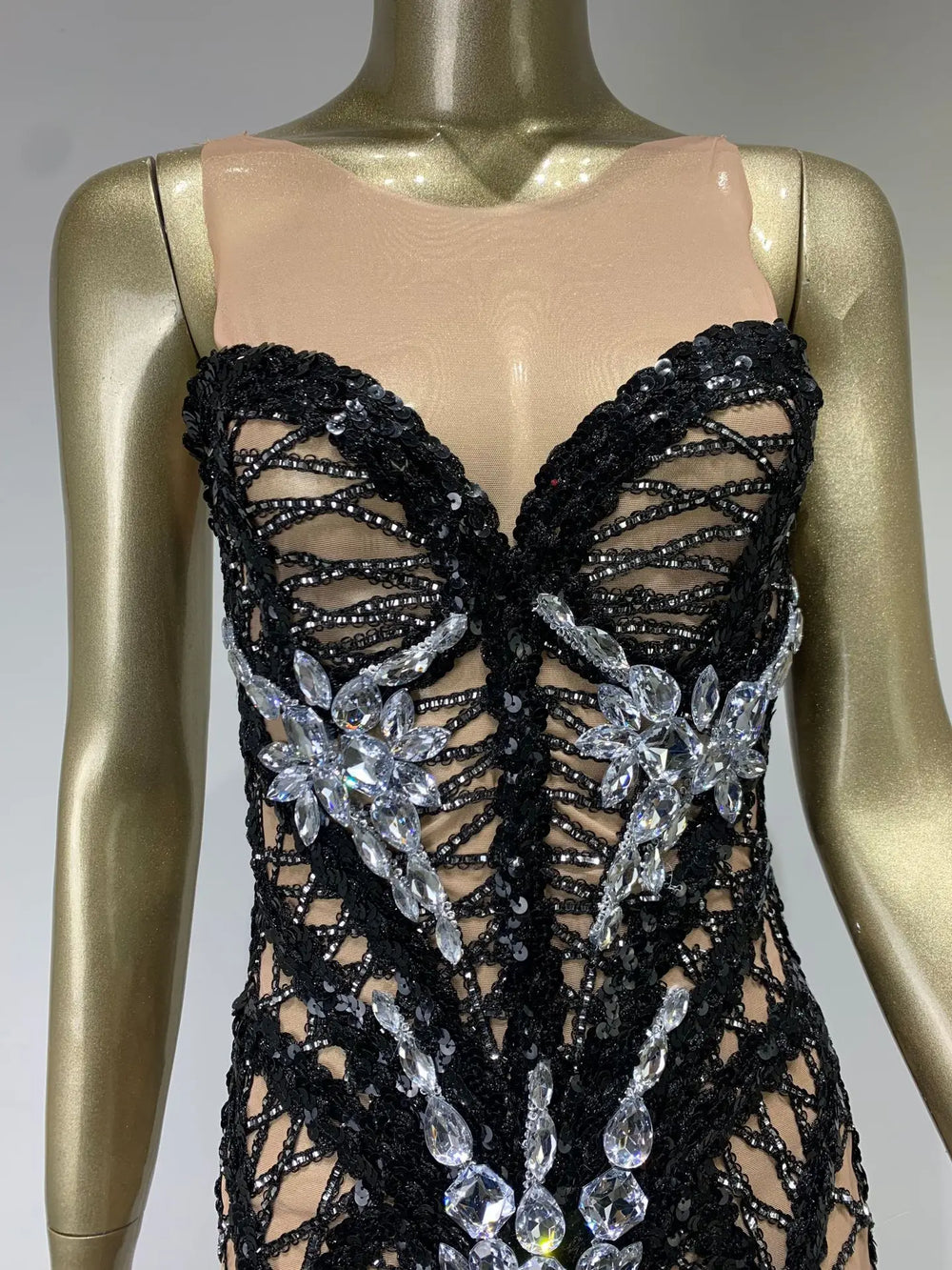 Black beaded and floral dress on a mannequin with a gold base.