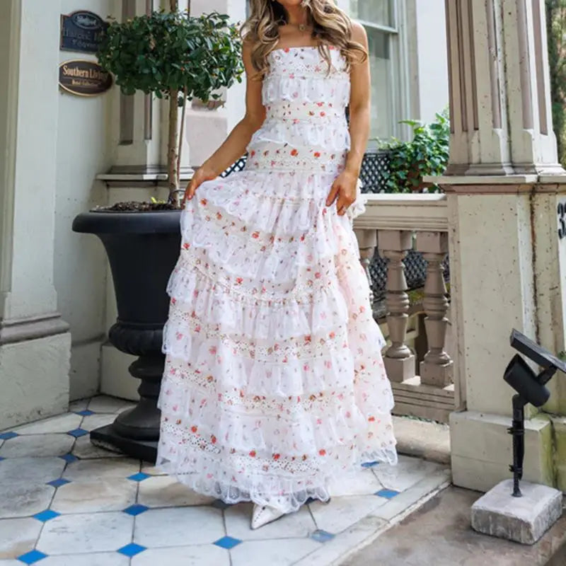 Woman in a white floral dress standing on a porch.