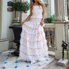Woman in a white floral dress standing on a porch.