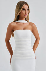 Woman wearing a white strapless dress against a plain background