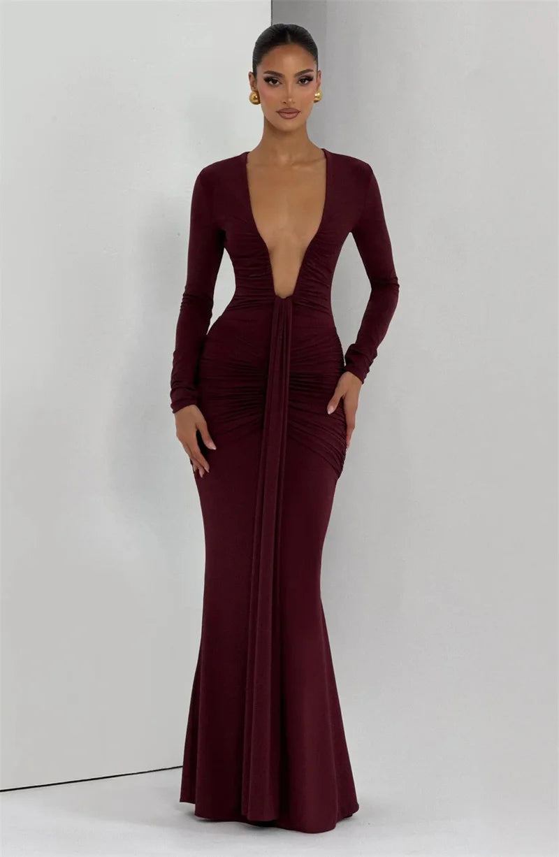 Woman wearing a burgundy evening gown with long sleeves on a white background
