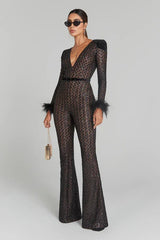 Woman wearing a black sequin jumpsuit with feathered sleeves on a gray background