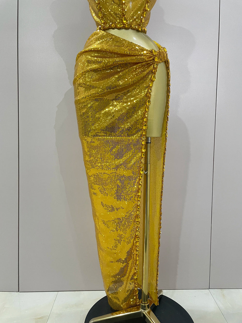 Mannequin wearing a gold sequin dress against a plain background