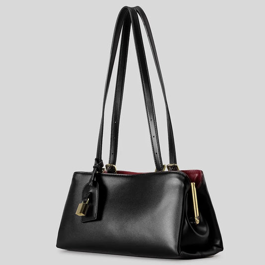 Black structured top handle bag with gold clasp closure and lock detail, angled view with longer straps.