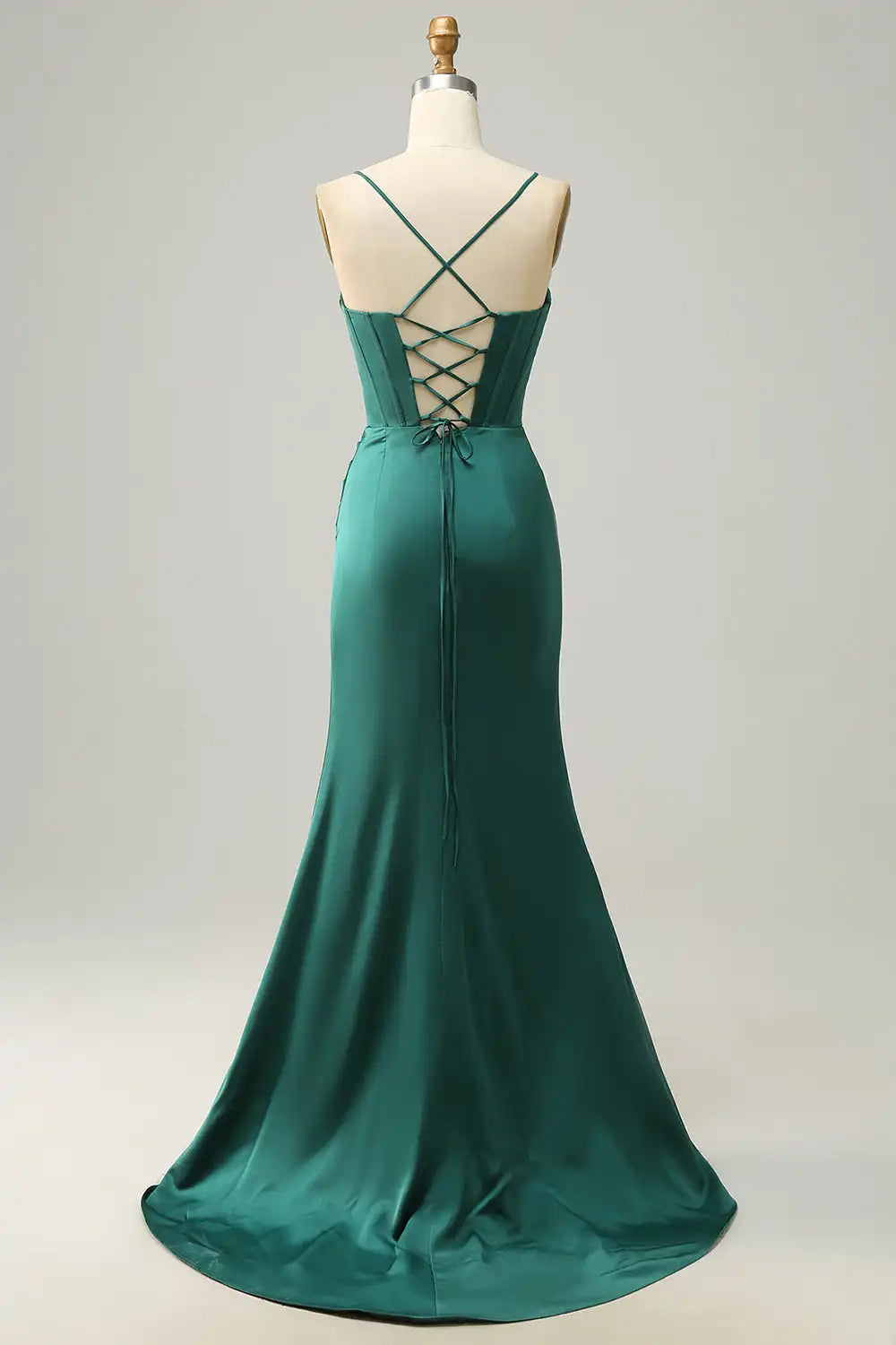 Green evening gown on a mannequin against a plain background