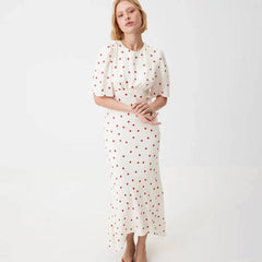 Model posing in a white polka dot midi dress