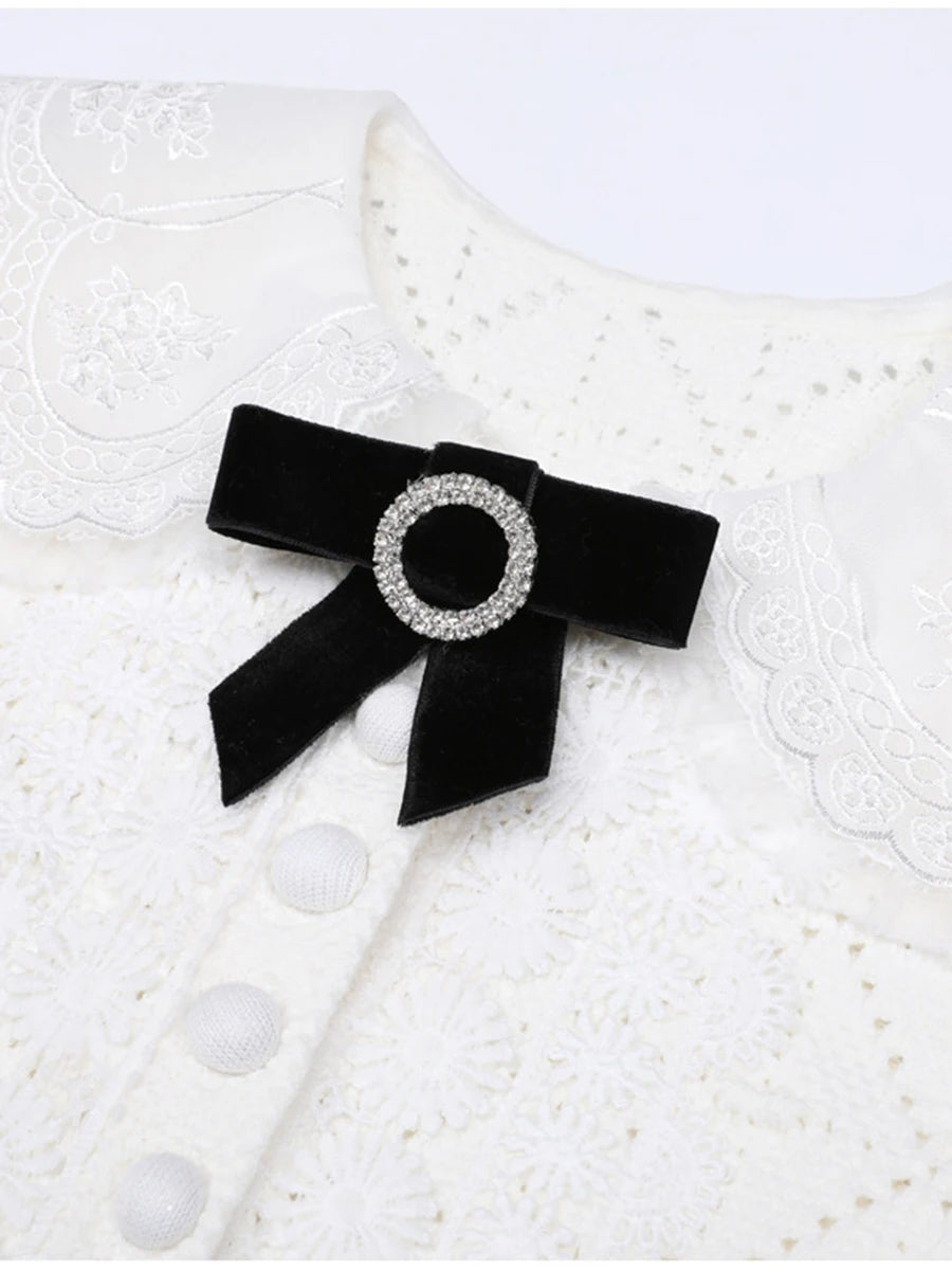 Black bow with a rhinestone center on a textured white background