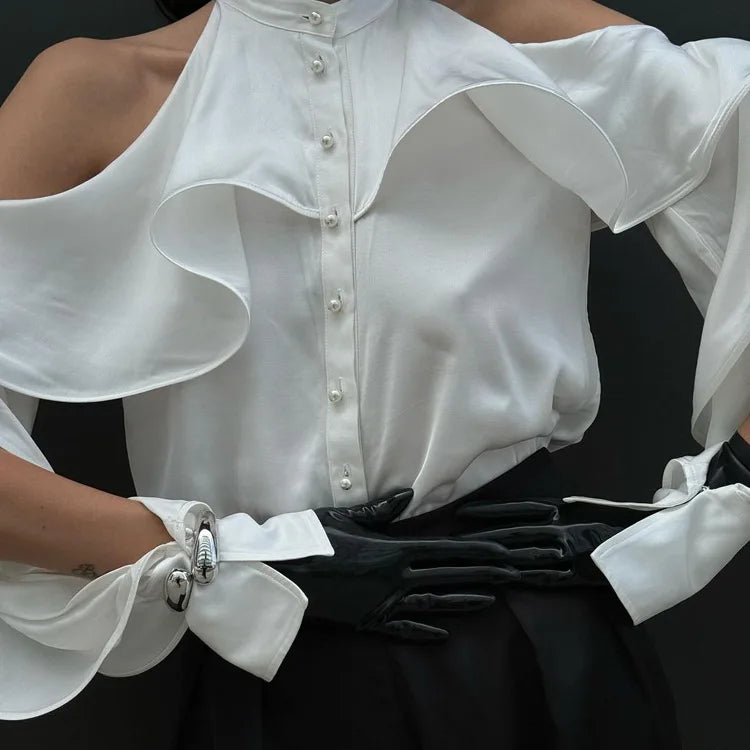 White blouse with ruffled shoulders and black gloves on a dark background