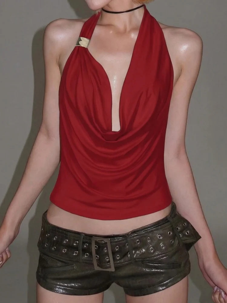Person wearing a red halter top and black leather shorts against a plain background