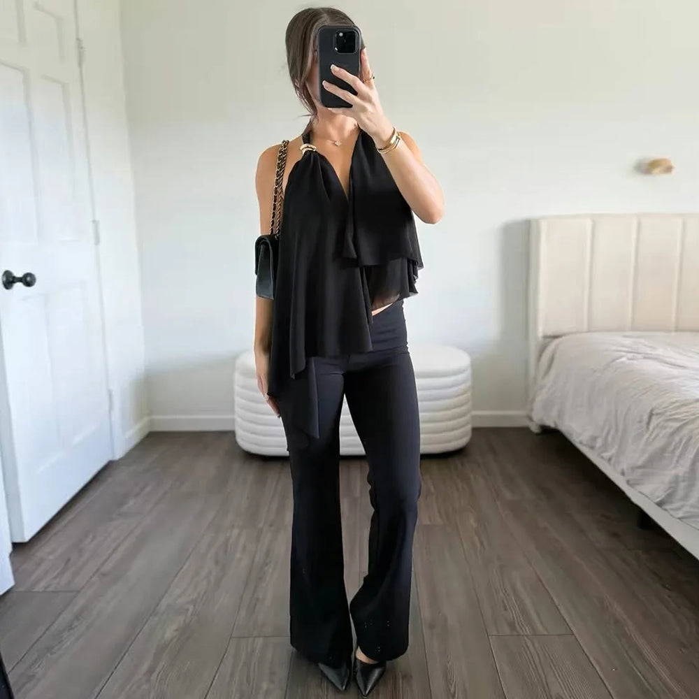 Person wearing a black outfit taking a mirror selfie in a bedroom.