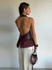Woman wearing a stylish outfit with a fringed top and holding a matching handbag against a plain background.