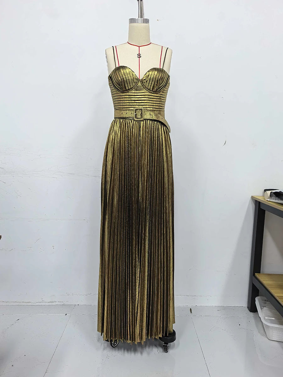 Gold pleated dress on a mannequin against a white wall.