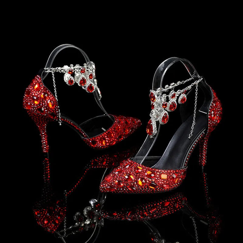 Red high-heeled shoes with gemstone embellishments on a black background