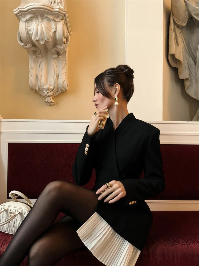 Woman in formal attire sitting on a red couch in an elegant room.