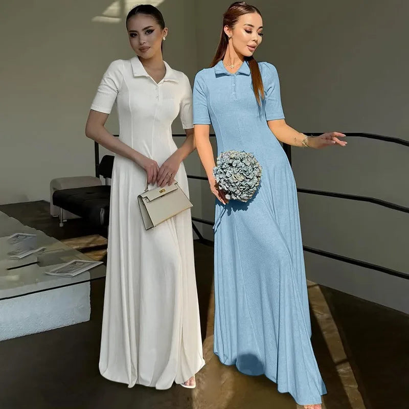 Two women in long dresses standing indoors, one in white and the other in blue.