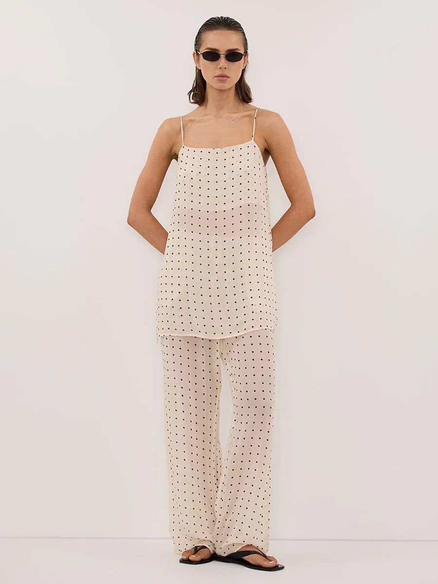 Woman wearing a polka dot dress with thin straps against a white background