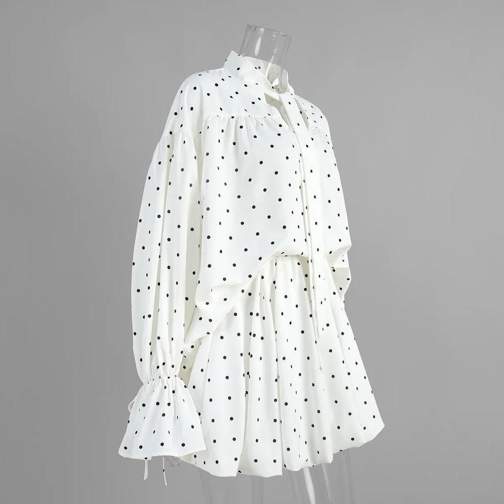 White blouse with black polka dots on a mannequin against a gray background