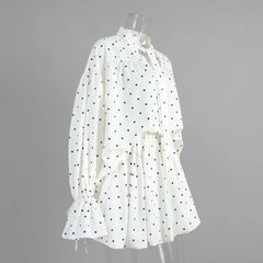 White blouse with black polka dots on a mannequin against a gray background