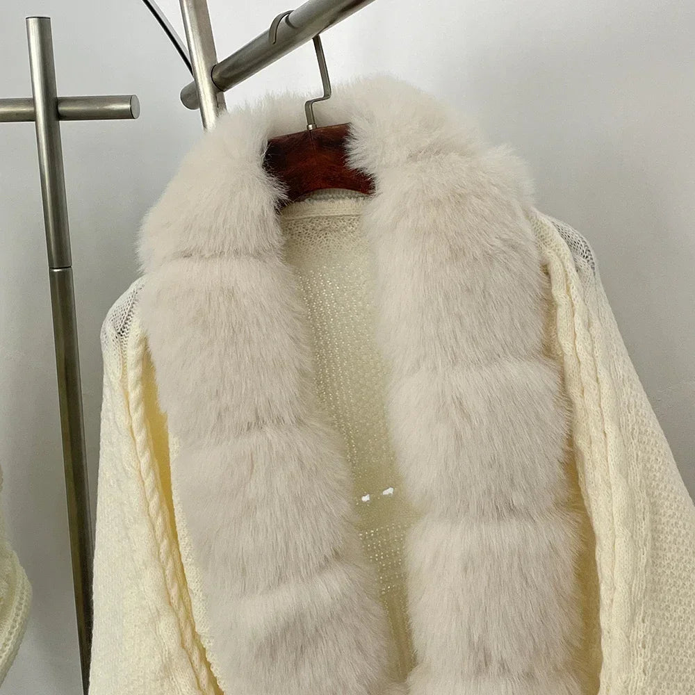 White fur vest over a cream sweater on a rack against a white background