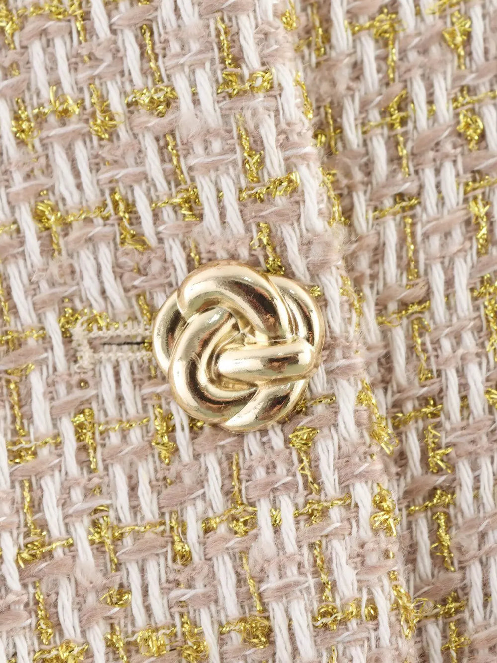 Close-up of a gold knot design on a textured fabric background