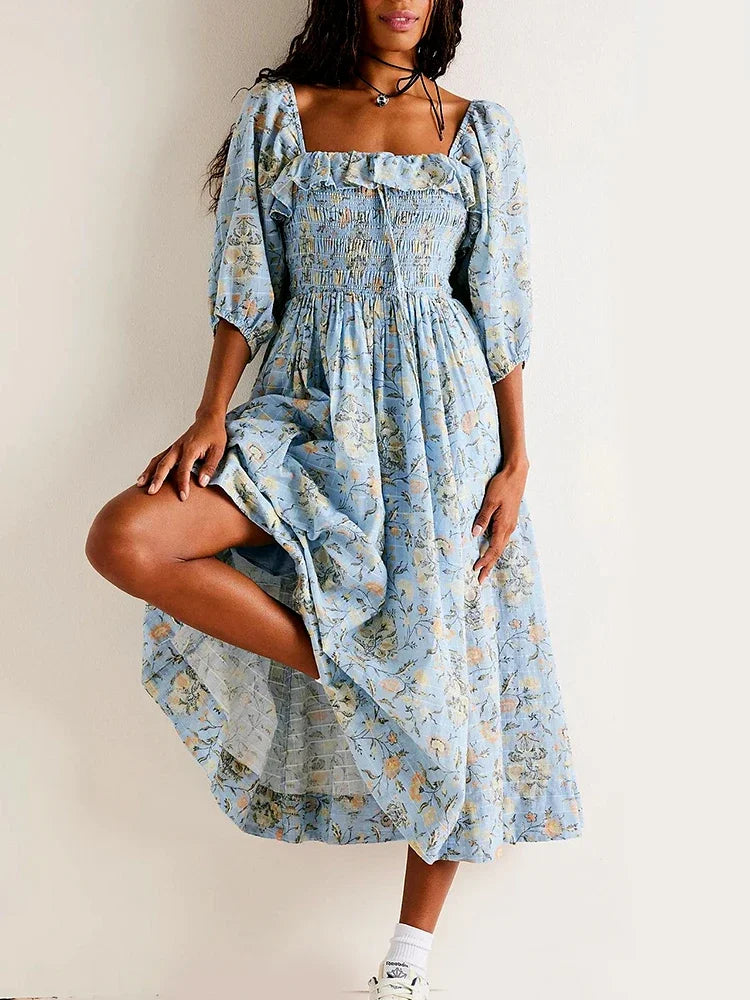 Woman wearing a blue floral dress against a plain background