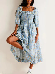 Woman wearing a blue floral dress against a plain background