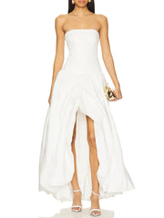 Woman wearing a strapless white dress with a high slit on a white background