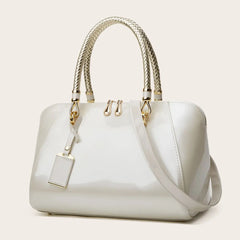 White patent leather Boston bag with braided handles and shoulder strap.