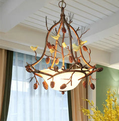Decorative chandelier with branches and birds in a room with curtains and flowers.