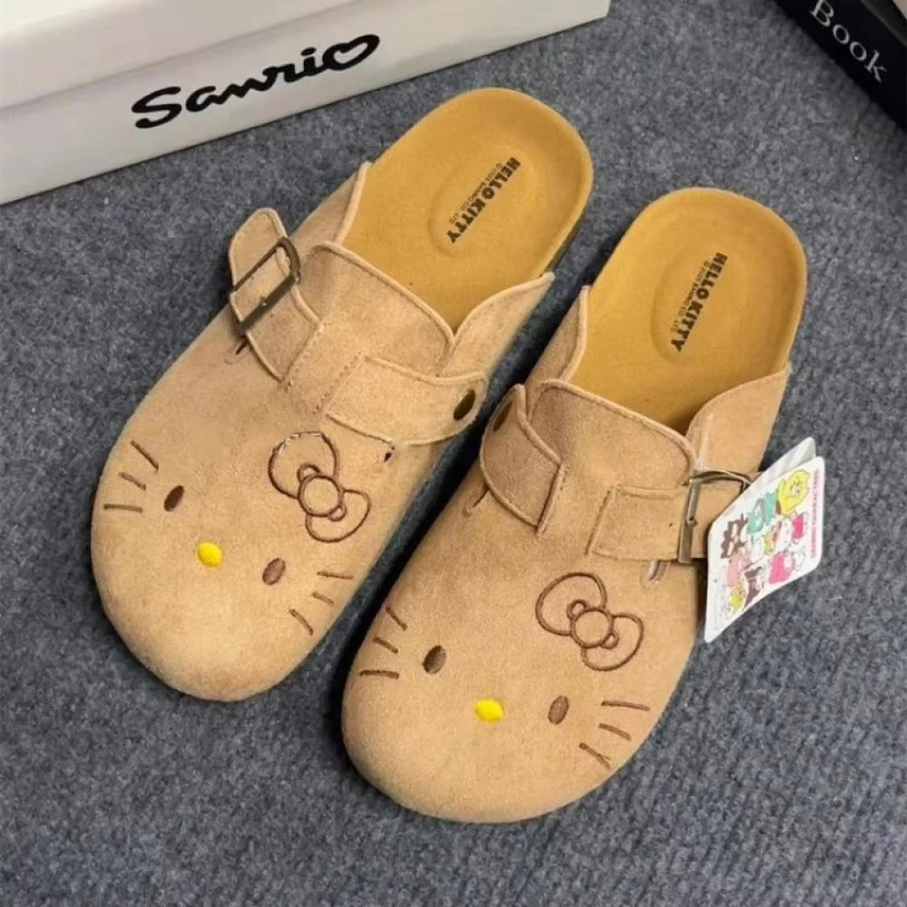 Tan Hello Kitty flat mule slippers with adjustable buckle strap and yellow nose detail.