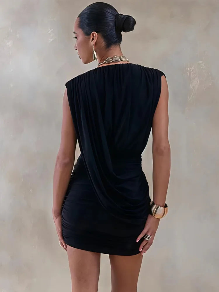 Woman wearing a black dress with a draped design against a neutral background
