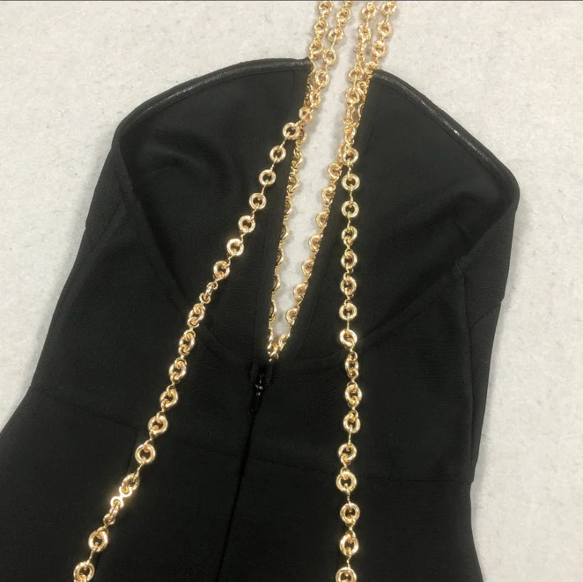 Gold chain draped over a black garment on a light gray background