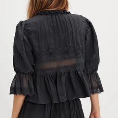 Black lace dress with sheer panels on a white background
