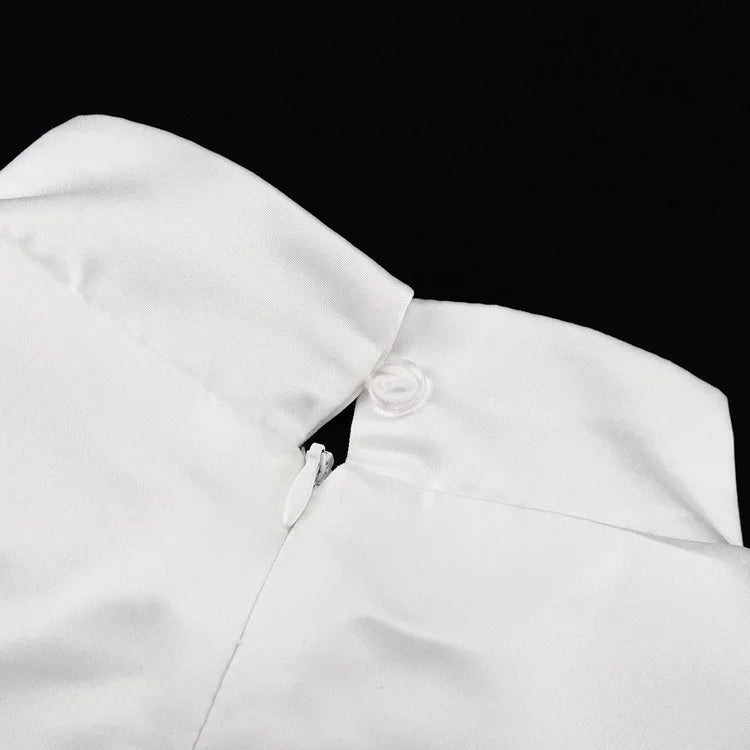 Close-up of a white garment with a collar and button on a black background