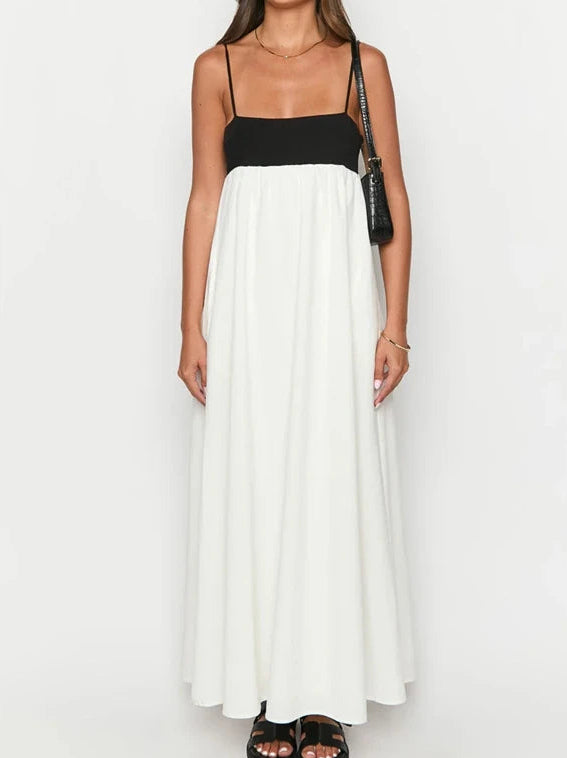 Woman wearing a black top and white flowing dress on a plain background