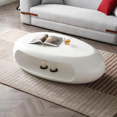 White oval coffee table with candles and a magazine in a living room setting.