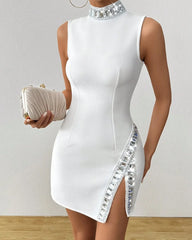 White dress with silver embellishments held by a person against a plain background