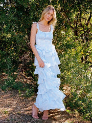 Woman wearing a light blue ruffled dress standing in a forest setting
