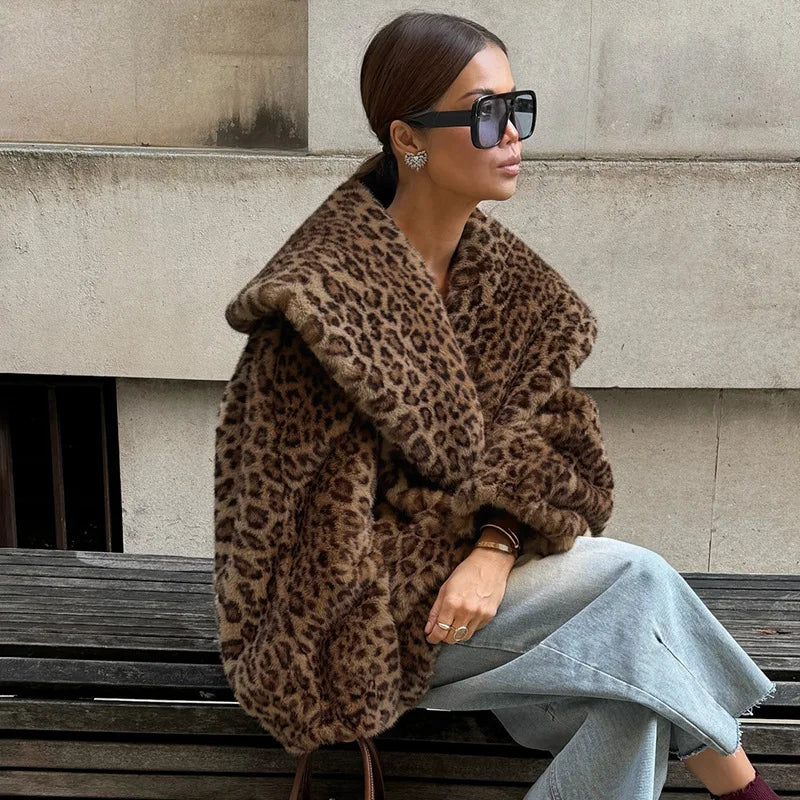 Woman wearing a leopard print coat sitting on a bench.