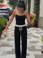Woman in black camisole top and wide-leg pants set with polka dot trim holding a drink